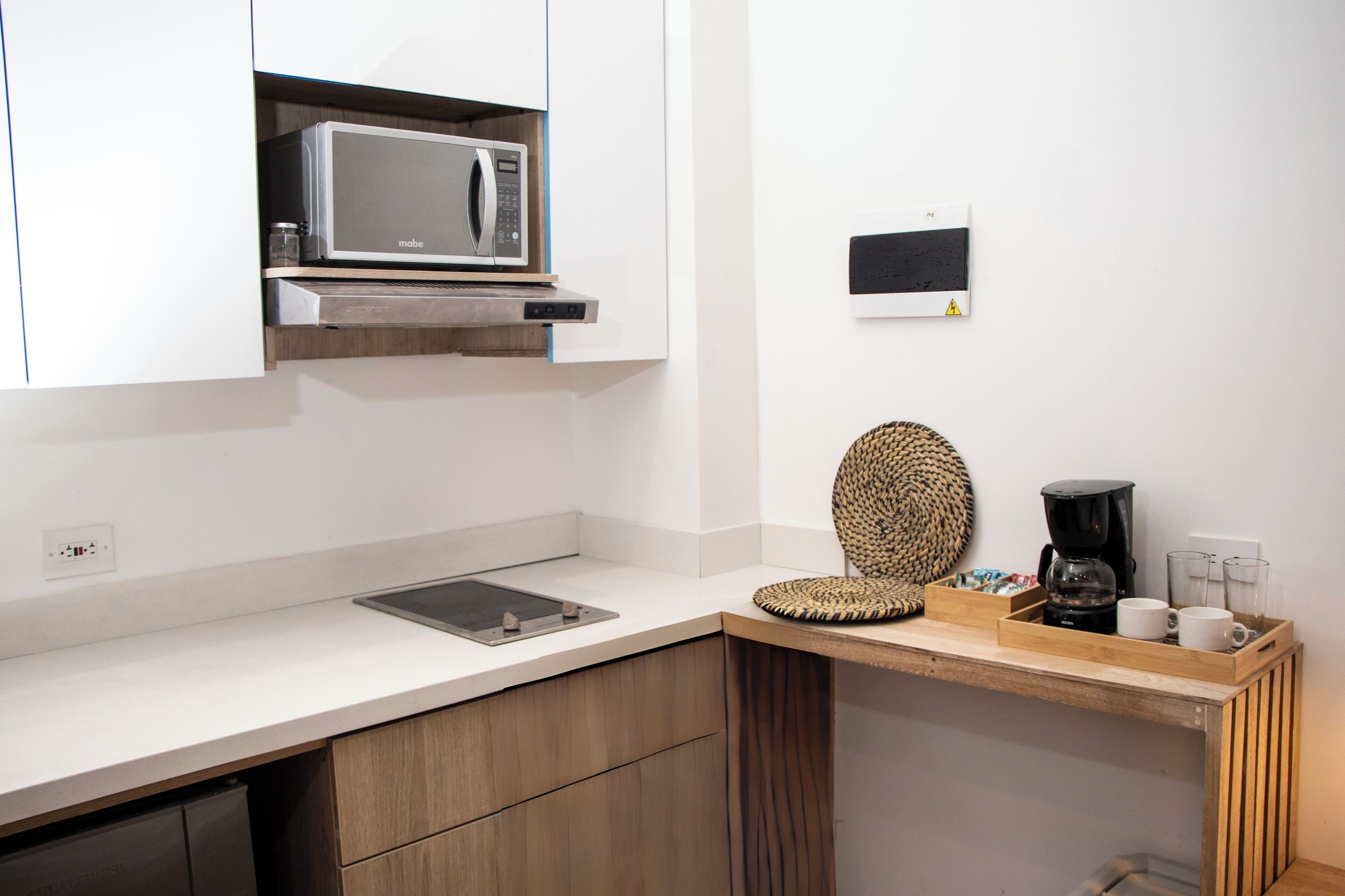 Una cocina con microondas, cafetera y una cesta tejida sobre la encimera.