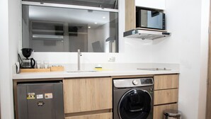 A compact kitchen with a dishwasher, washing machine, and a microwave above the counter. - zenia (Medellín)