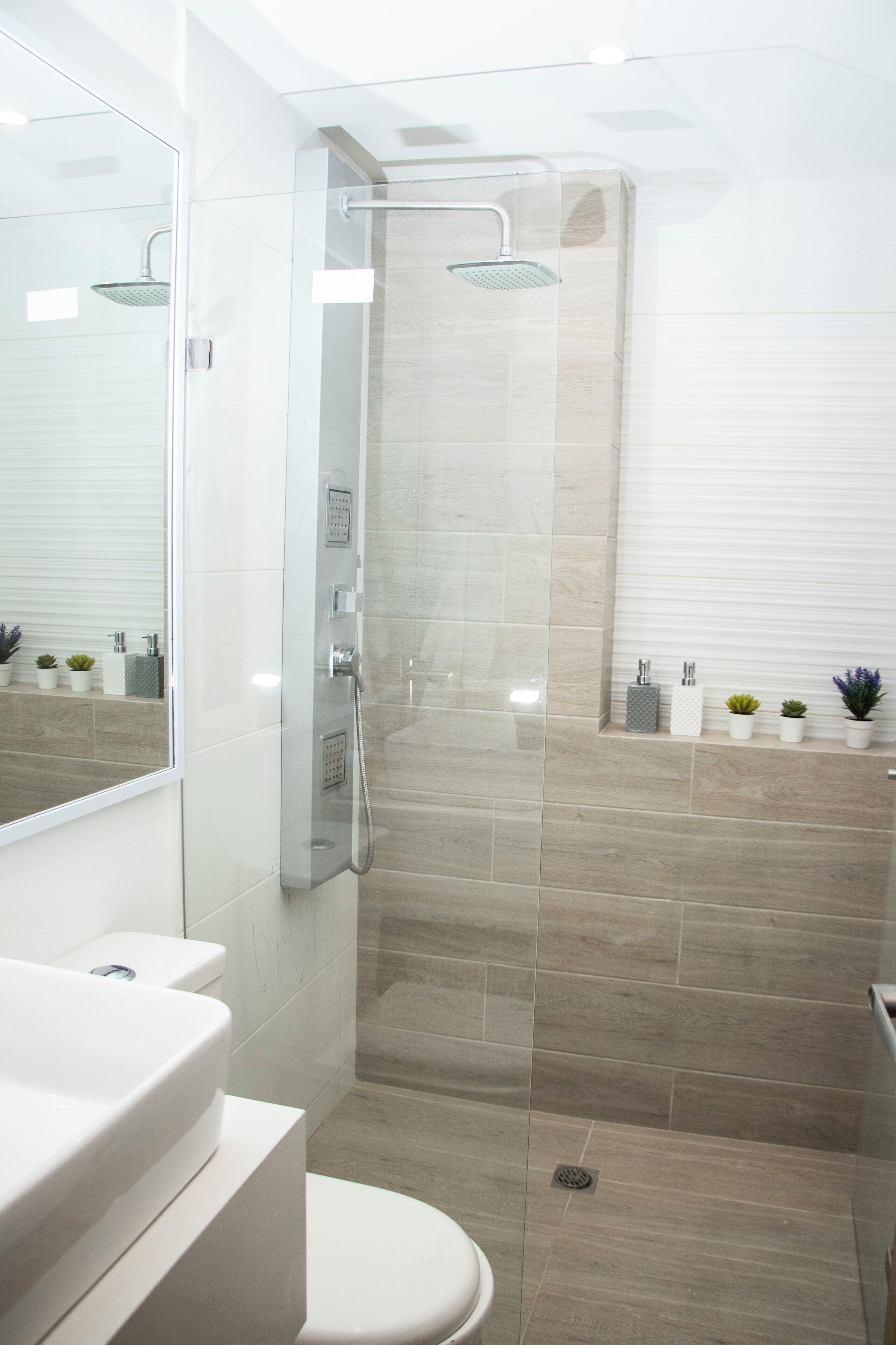 Une salle de bain moderne avec une douche à parois de verre, un lavabo blanc et des toilettes.
