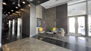 En moderne lobby med marmorgulv, en receptionsdisk og et siddeområde med en plante.