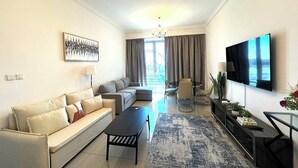 En moderne stue med sofa, sofabord, fjernsyn og et spiseområde med stole og bord.