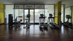 Et fitnesscenter med forskelligt træningsudstyr til cardio og styrketræning, store vinduer og motiverende plakater på væggene.