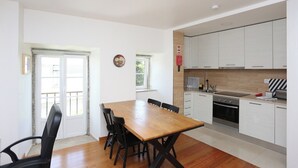 Uma cozinha moderna com armários brancos, uma mesa de jantar de madeira e cadeiras pretas.