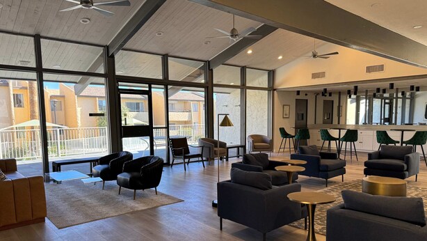 A spacious lounge area with modern furniture, large windows, and ceiling fans. - Thomas Rd Oasis (Scottsdale)