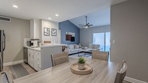 A modern kitchen with white cabinets, a microwave, and a dining area with a wooden table and chairs. - Thomas Rd Oasis (Scottsdale)