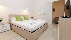 A modern hotel room with a wooden bed, white bedding, a bedside table with a lamp, and a small plant. - VivimiHome-Duomo Cioffi House (Milan)