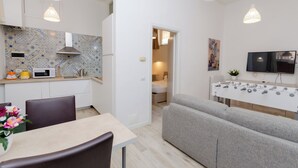 A compact living space with a kitchenette, a dining area, a sofa, and a TV. - VivimiHome-Duomo Cioffi House (Milan)