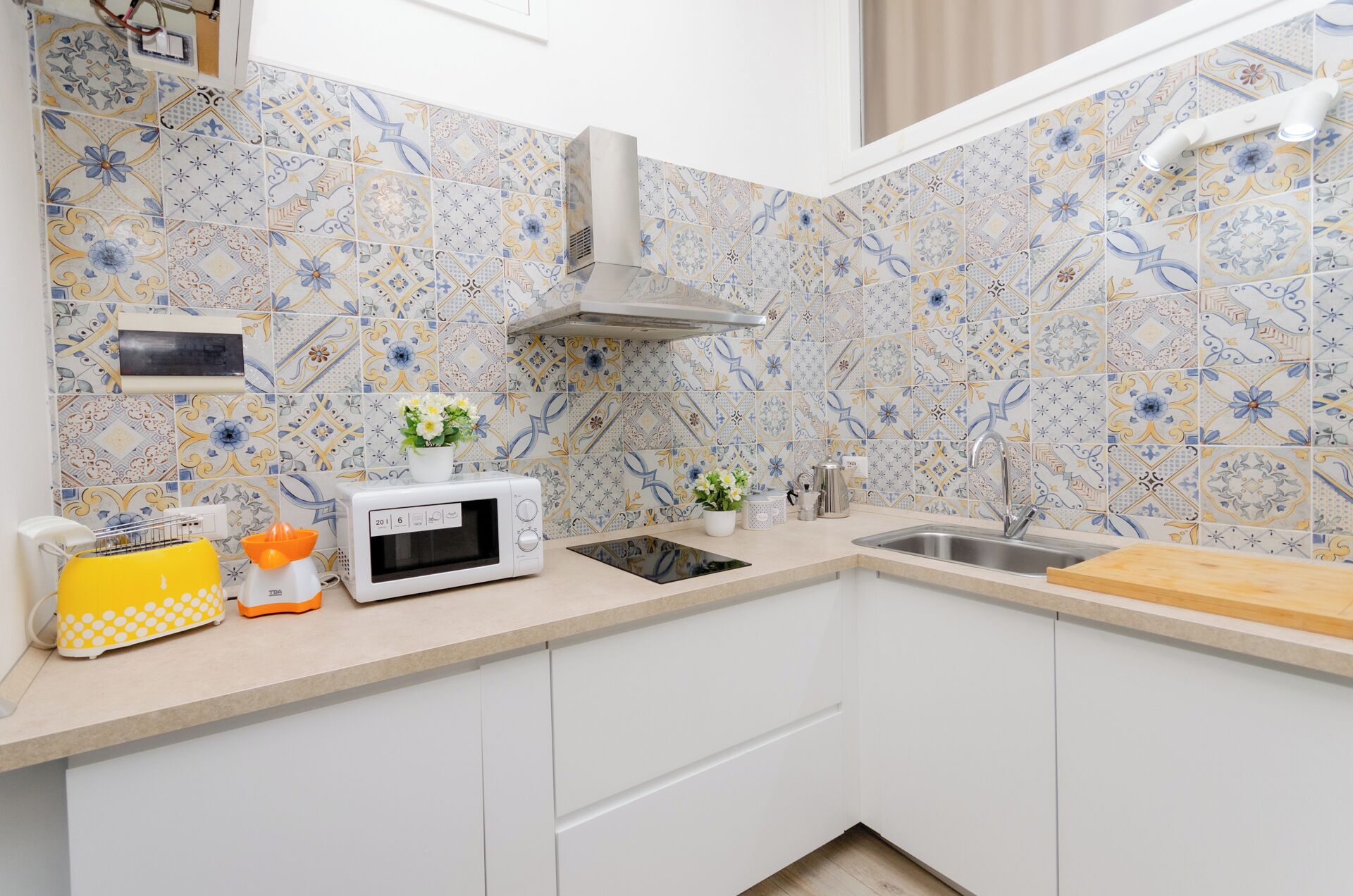 A kitchen with a microwave, sink, and a decorative backsplash.