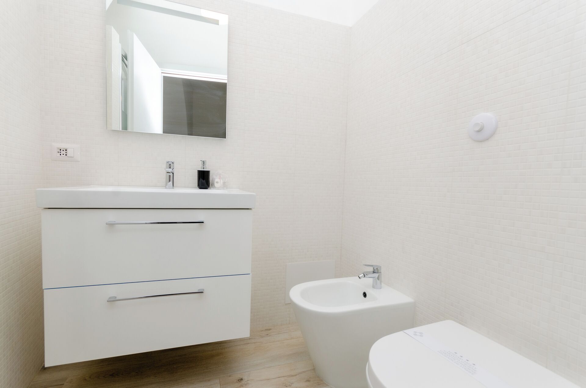 Un baño moderno con tocador blanco, un bidé y un inodoro.