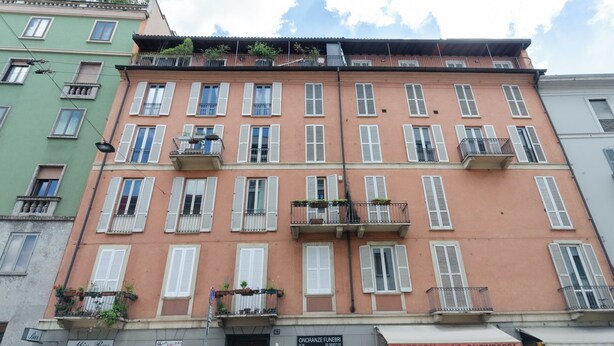 A multi-story building with balconies, storefronts, and a street view. - VivimiHome-Duomo Cioffi House (Milan)