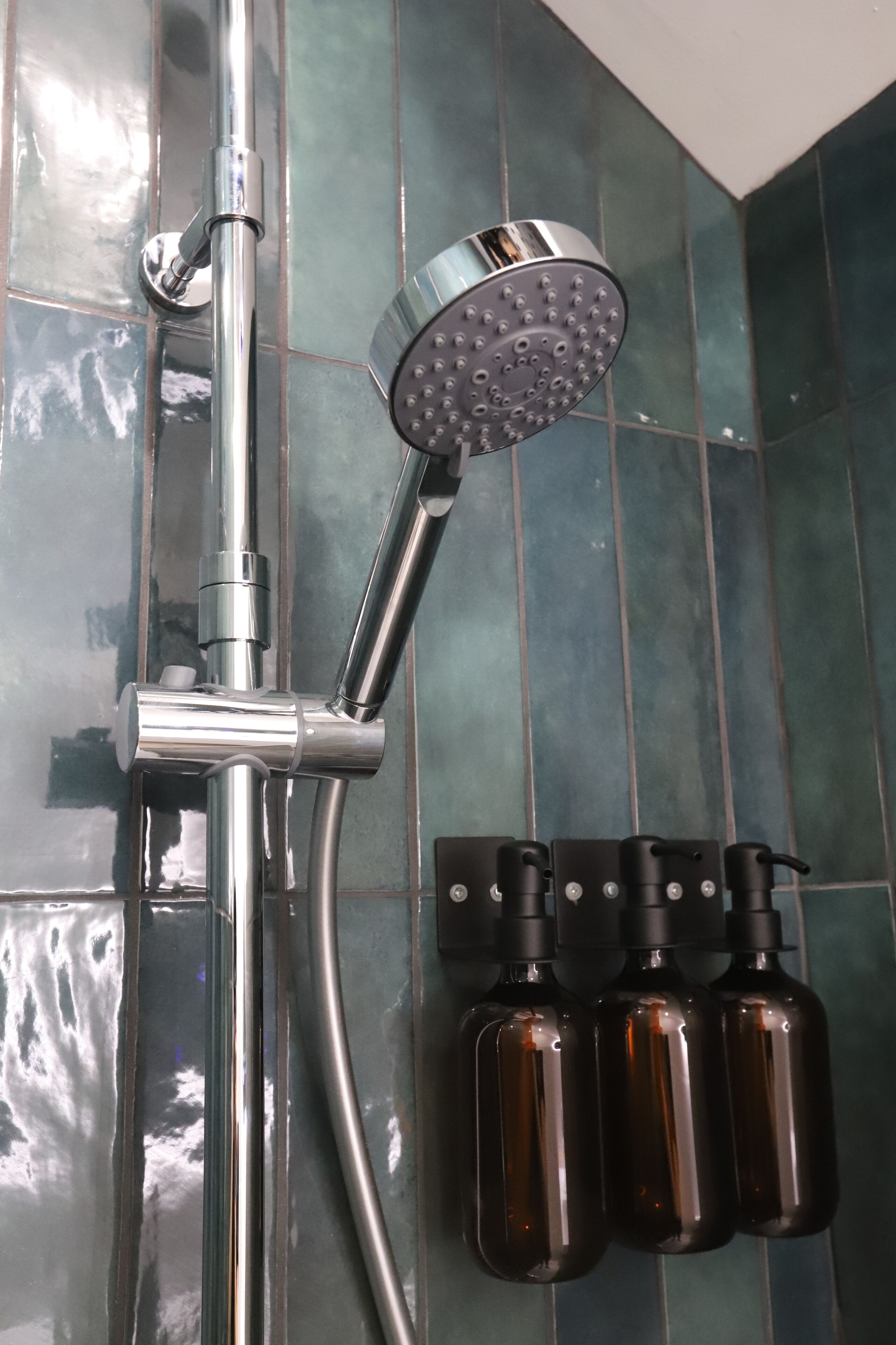 A shower with a handheld showerhead and a wall-mounted control panel.