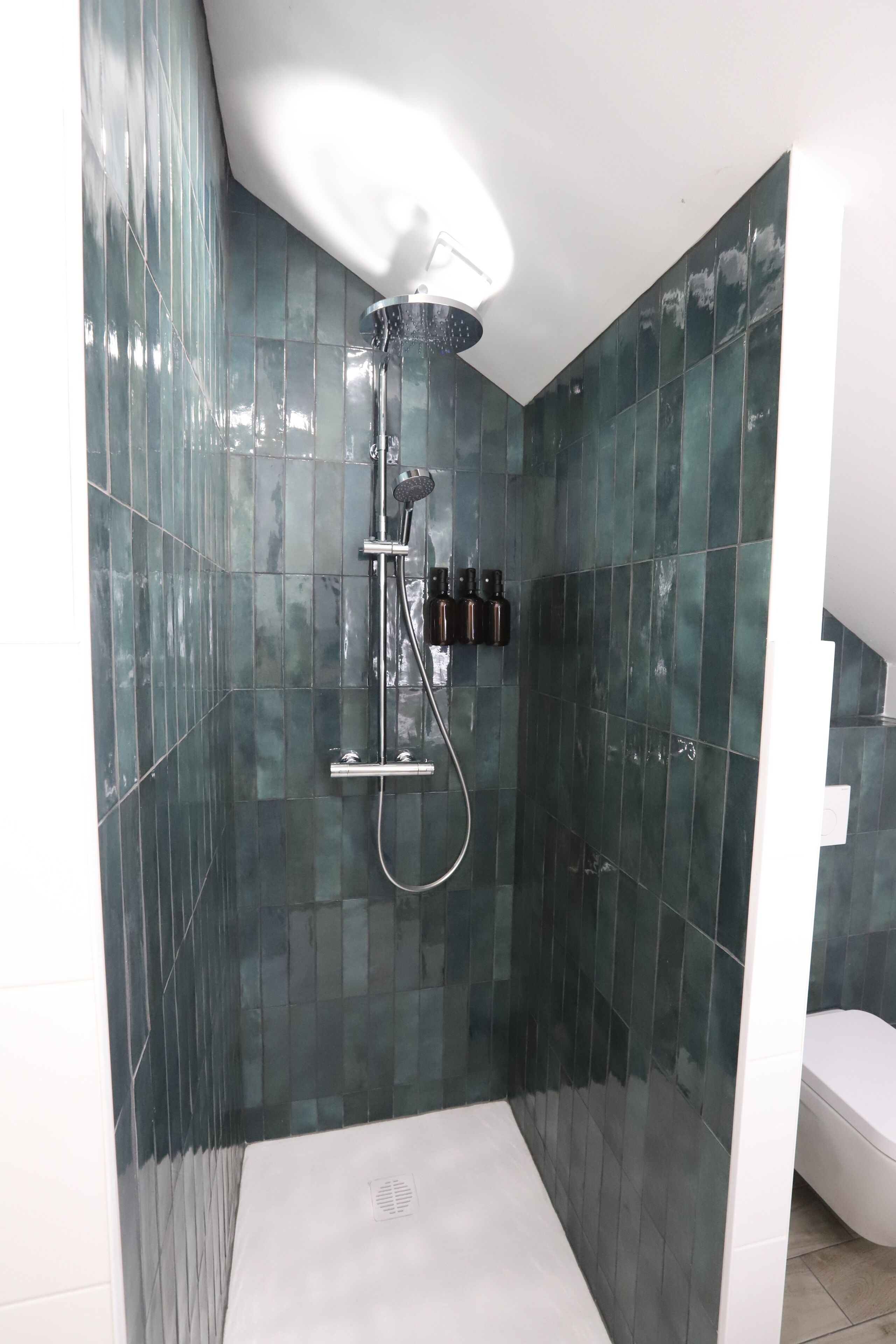 Ein modernes Duschbad mit Glasabtrennung, Handbrause und Armatur an der Wand.