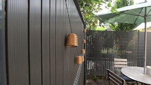 A patio area with a metal fence, a table with chairs, and a hanging basket.