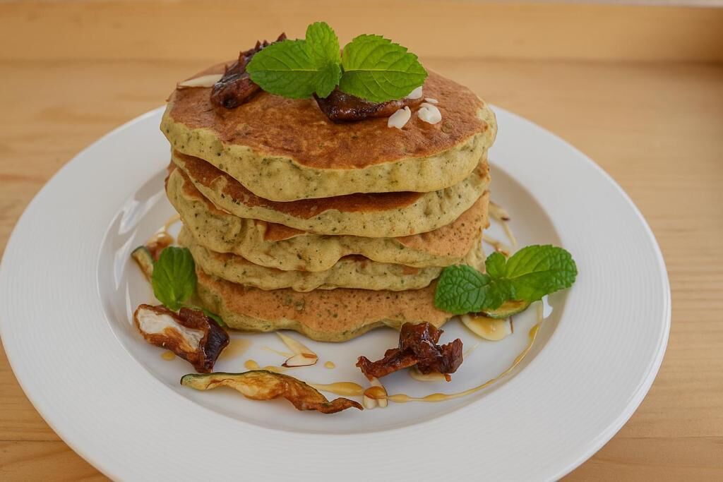 Ein Stapel Pfannkuchen mit Ahornsirup und Minzblättern garniert.