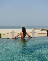 A woman in a pool with a view of a beach and ocean.