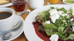 A table with breakfast items including toast, a glass of orange juice, a cup of tea, a bowl of soup, and a salad with a red sauce. - Altstadt Hotel Wertheim (Wertheim)