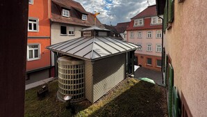 A courtyard with a metal roof structure, a cylindrical water tank, and adjacent buildings with red and pink facades. - Altstadt Hotel Wertheim (Wertheim)
