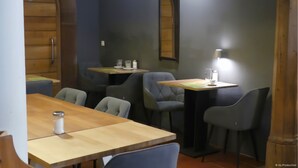A dining area with wooden tables and grey upholstered chairs. - Altstadt Hotel Wertheim (Wertheim)