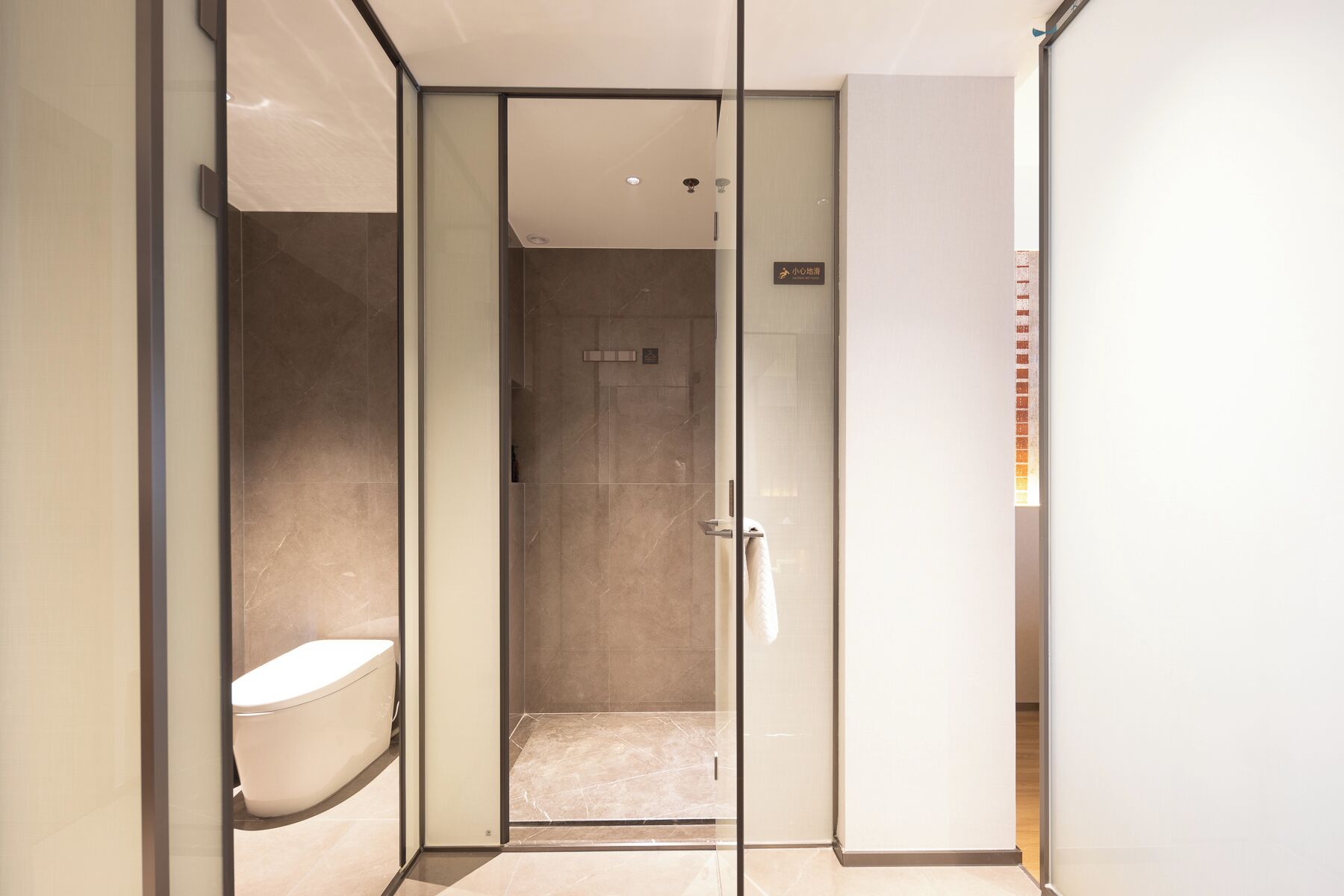 Un bagno moderno con il water, cabina doccia in vetro e cartello che indica area fasciatoio.