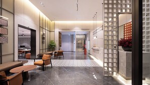 Un moderno vestíbulo de hotel con área de descanso, una mesa de recepción y una pared decorativa con un diseño geométrico.