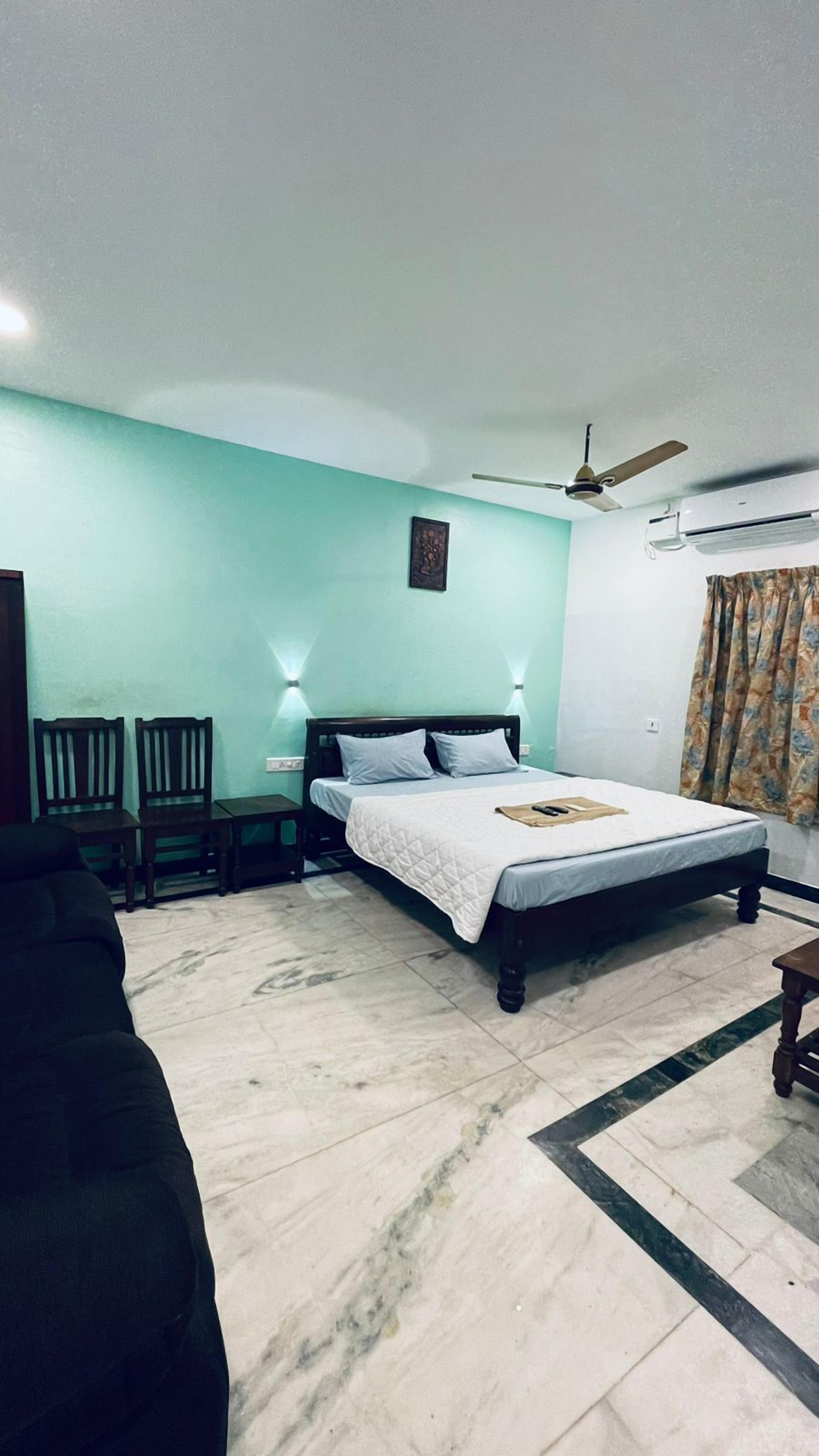 A bedroom with a bed, a ceiling fan, an air conditioning unit, and a nightstand.