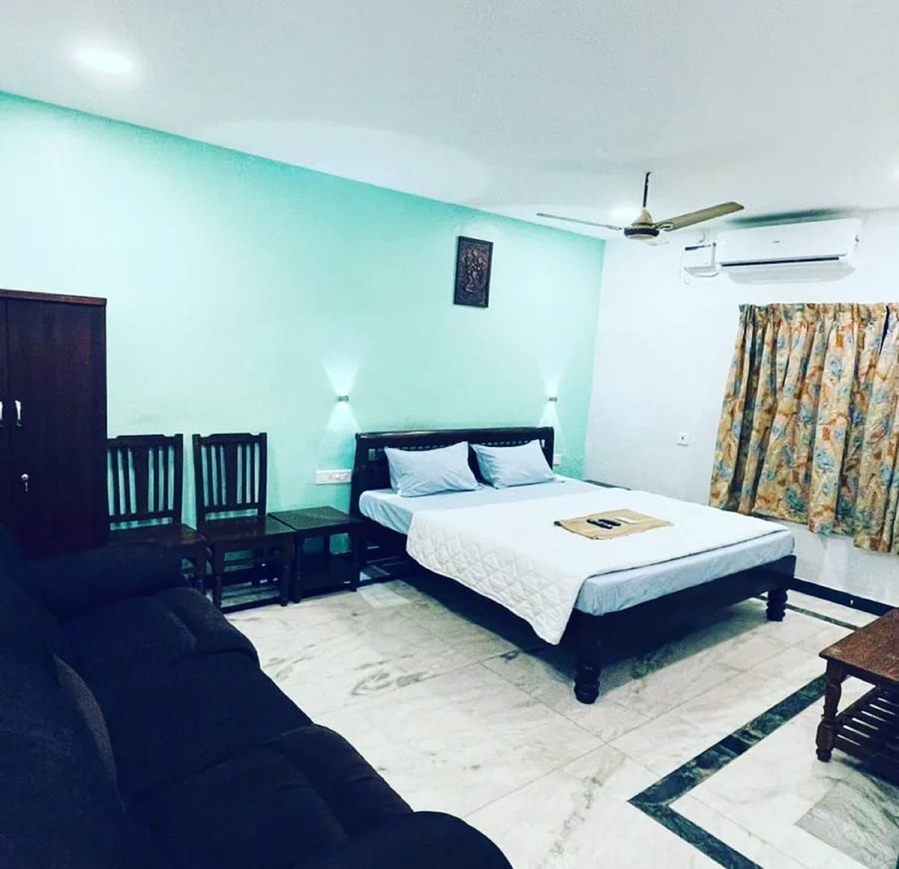 A bedroom with a bed, a desk, a chair, a wardrobe, and a ceiling fan.