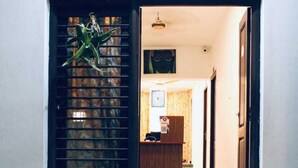 A hotel entrance with a reception desk, a welcome mat, and a staircase leading inside. - VCP Beach Resort (Puducherry)