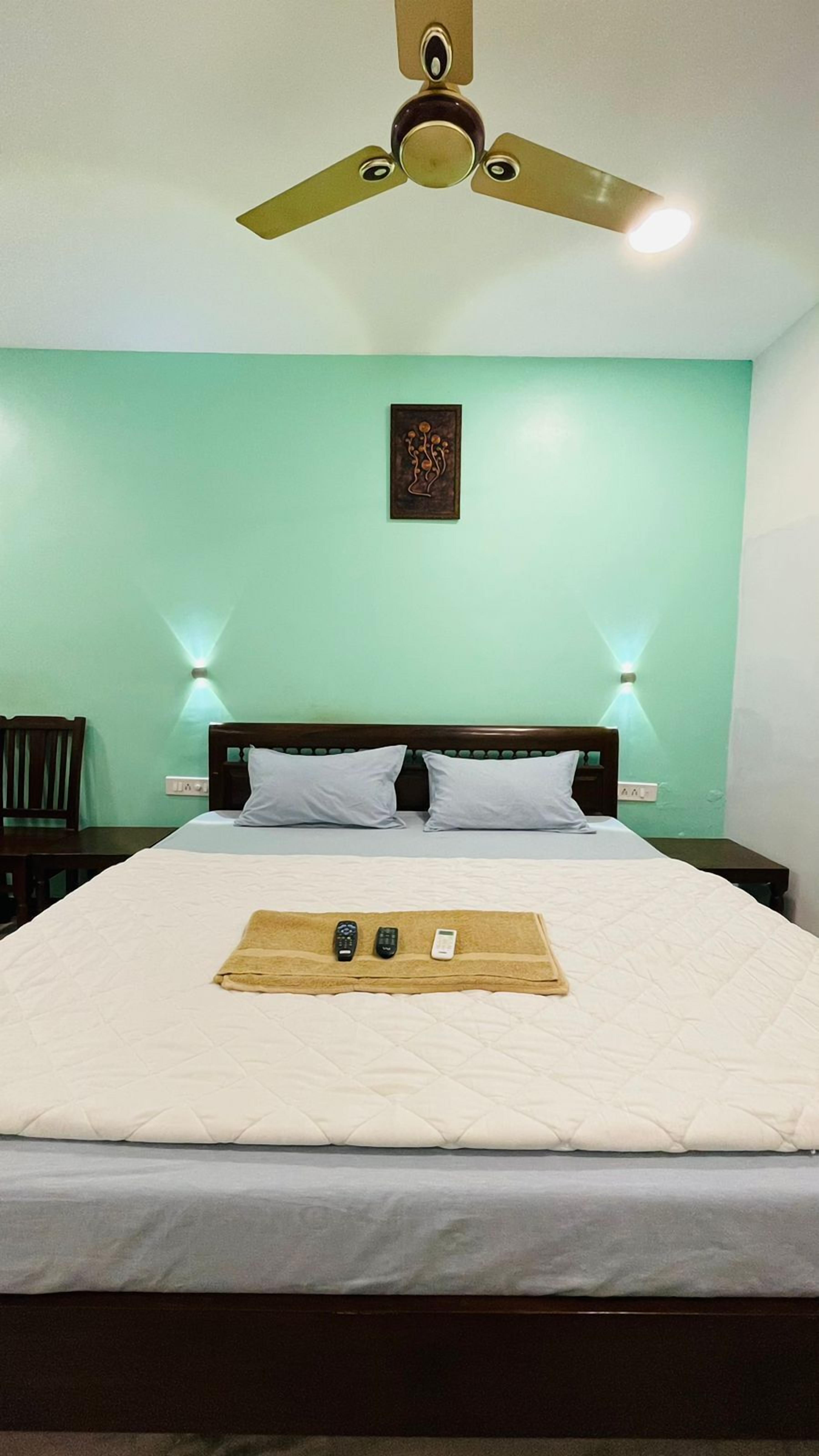 A neatly made bed with a wooden headboard, two bedside lamps, and a ceiling fan.