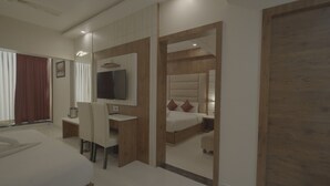 Una camera d'hotel moderna con un letto grande, una scrivania con una sedia, una TV fissata al muro e una porta in legno.