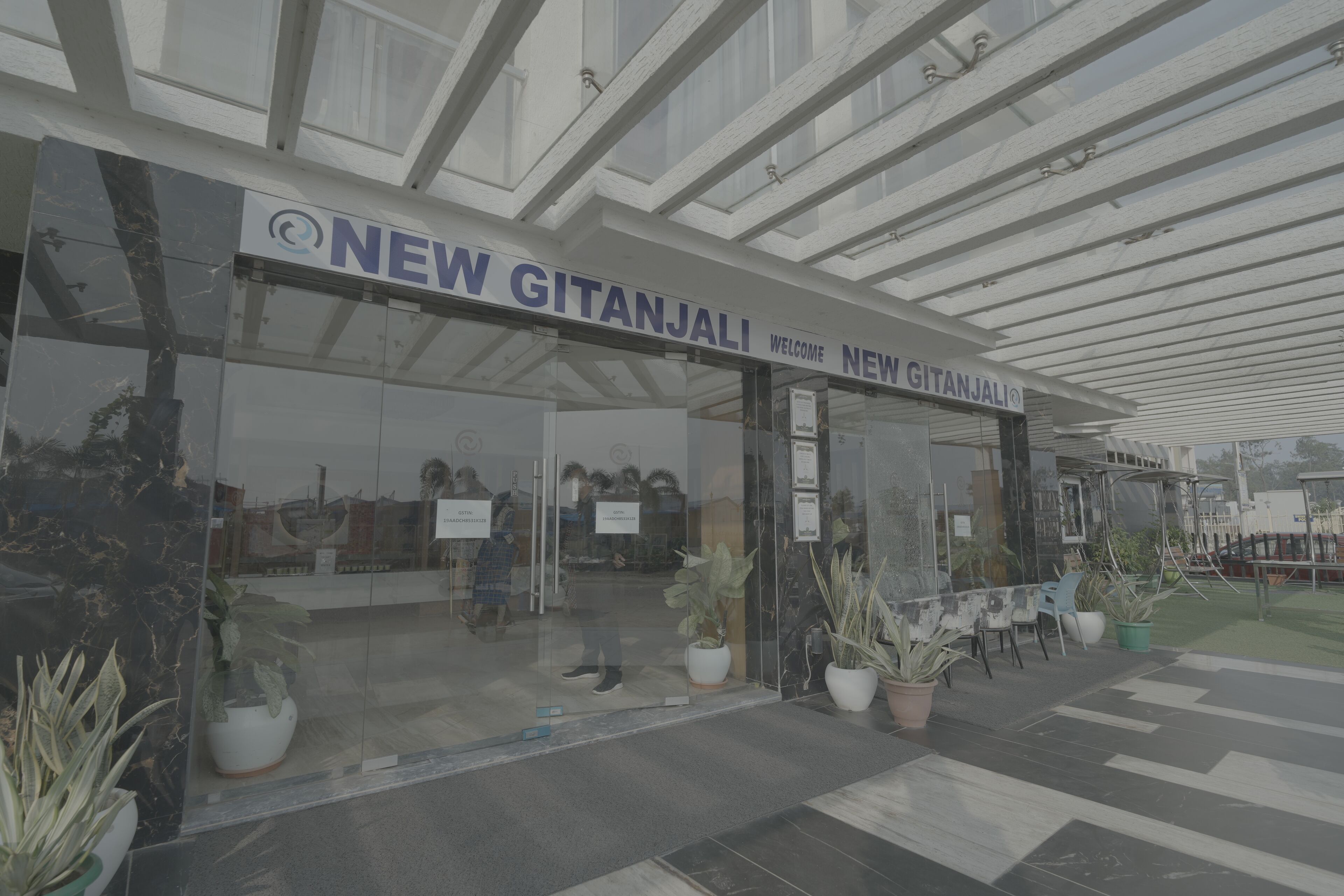 A modern building with a glass facade and a sign reading "NEW GITANJALI".