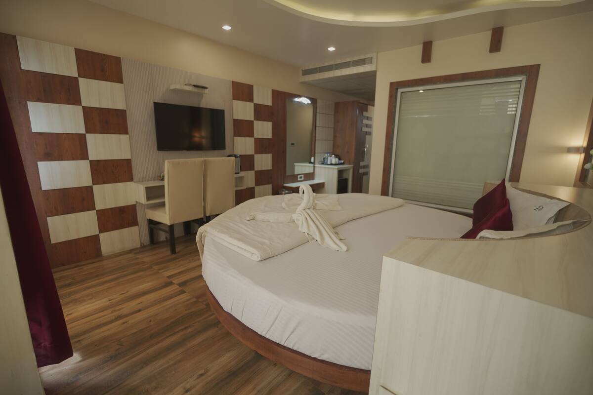 Una habitación de hotel con una cama grande, un escritorio, una silla, un televisor y un espejo.