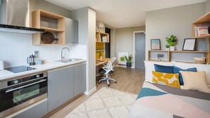 A modern kitchen with built-in appliances, a dining area with a table and chairs, and a living room with a sofa and decorative pillows. - Student Only Zinc Quarter (Bristol)