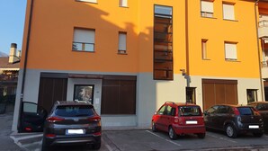 Un edificio de varios pisos con una fachada naranja brillante, varias ventanas y una puerta de garaje visible.