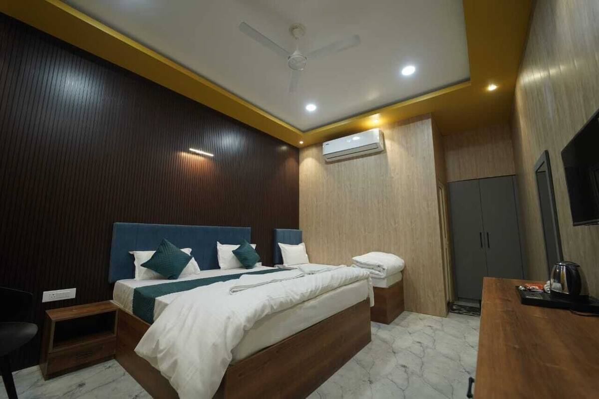 A modern bedroom with a bed, bedside tables, a ceiling fan, an air conditioning unit, and a TV.
