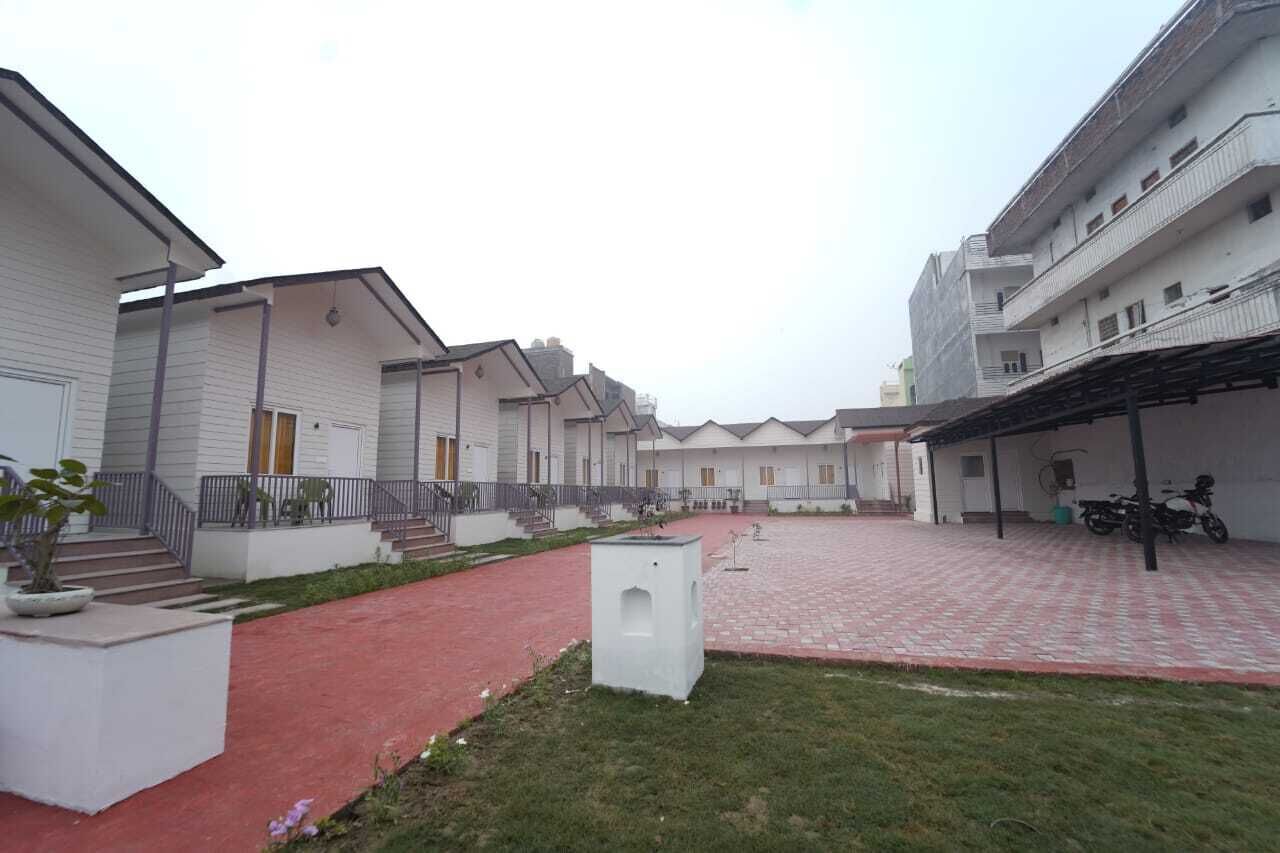 A courtyard with white buildings, a red brick pathway, and a small garden area.