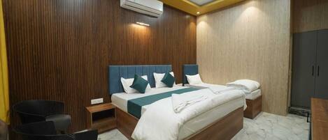 A hotel room with a wooden panel wall, a bed with white bedding, a nightstand, a chair, and a wardrobe.