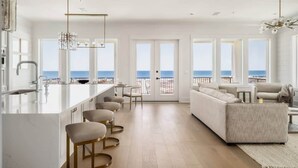 Eine moderne Küche mit Bar, großen Fenstern und Meerblick.