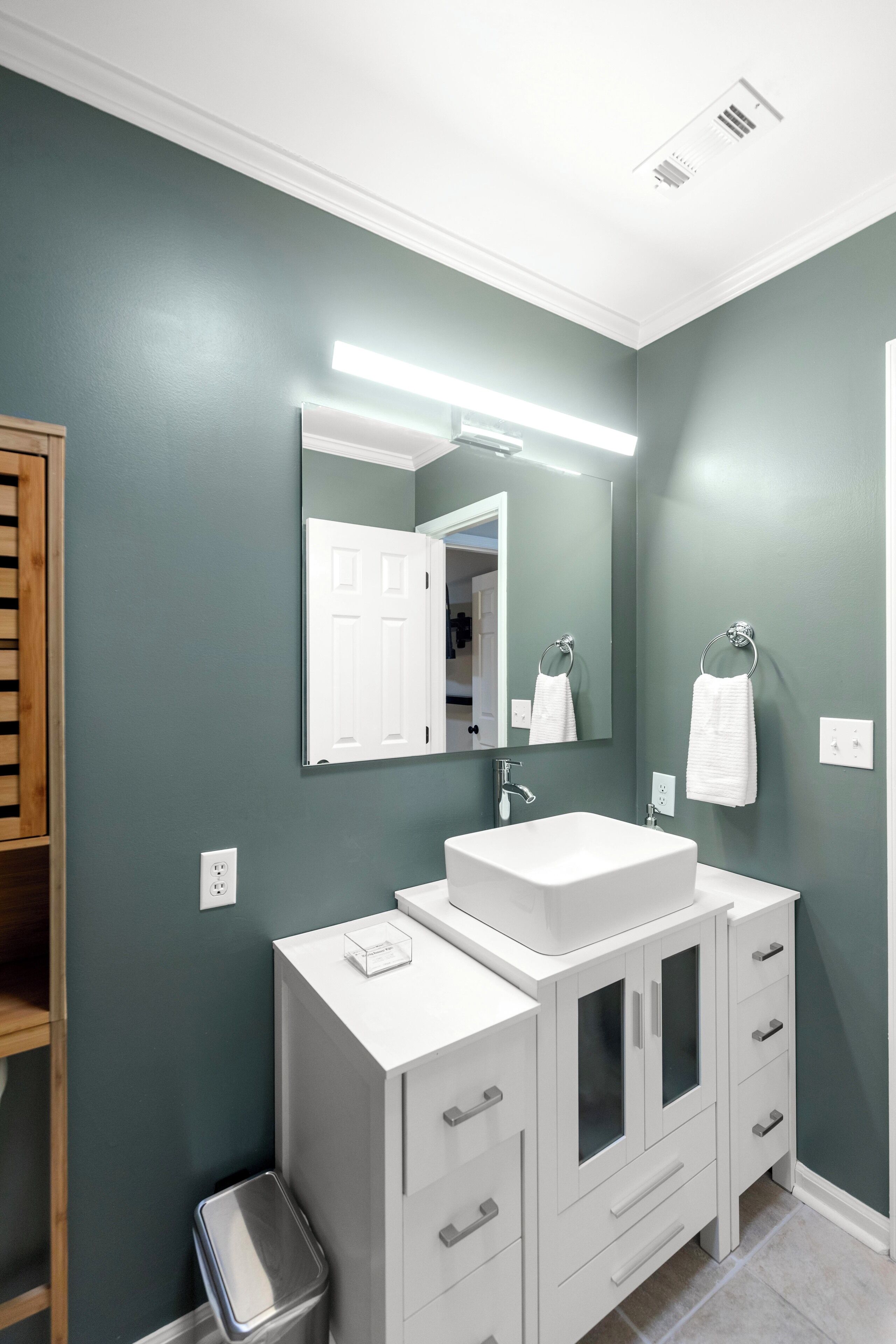 A bathroom with a white vanity, a large mirror, and a towel ring.