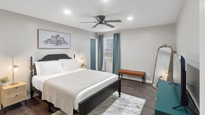 A bedroom with a bed, bedside tables, a ceiling fan, a large mirror, and a TV. - Renovated 3 Bed 2 Bath,Dog Friendly, Game Room, Fenced Yard, Well Equipped Kitchen, 5 Smart TVs (Dothan)
