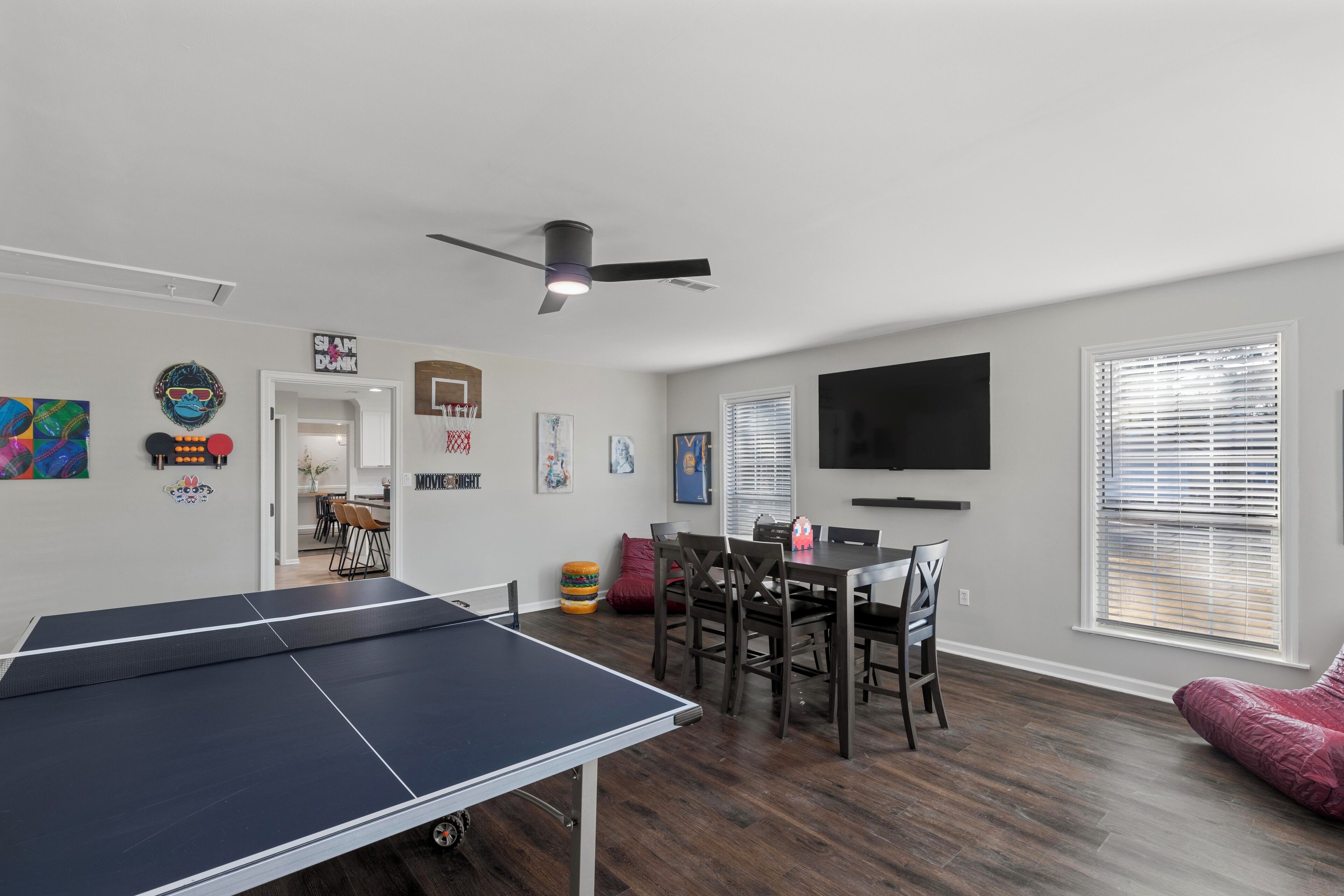 A modern living room with a ping pong table, dining area, and a flat-screen TV.