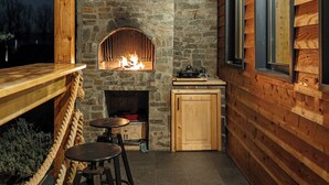 Un interior rústico de madera con chimenea de piedra, bancos de madera y un pequeño armario de madera.