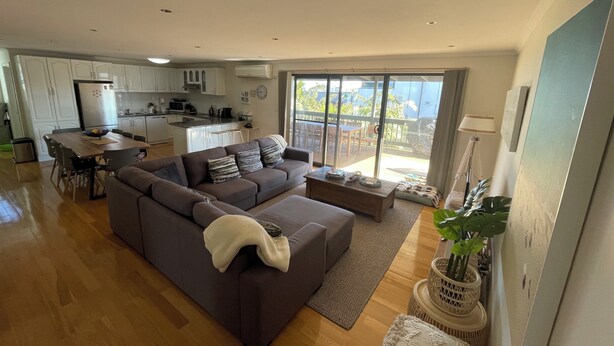 A modern living room with a sectional sofa, a dining table, and a kitchen area.