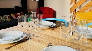 A dining area with a wooden table set for a meal, surrounded by potted plants, a red chair, and a colorful painting on the wall. - Les gîtes de Wissembourg- Color Lodge (Wissembourg)
