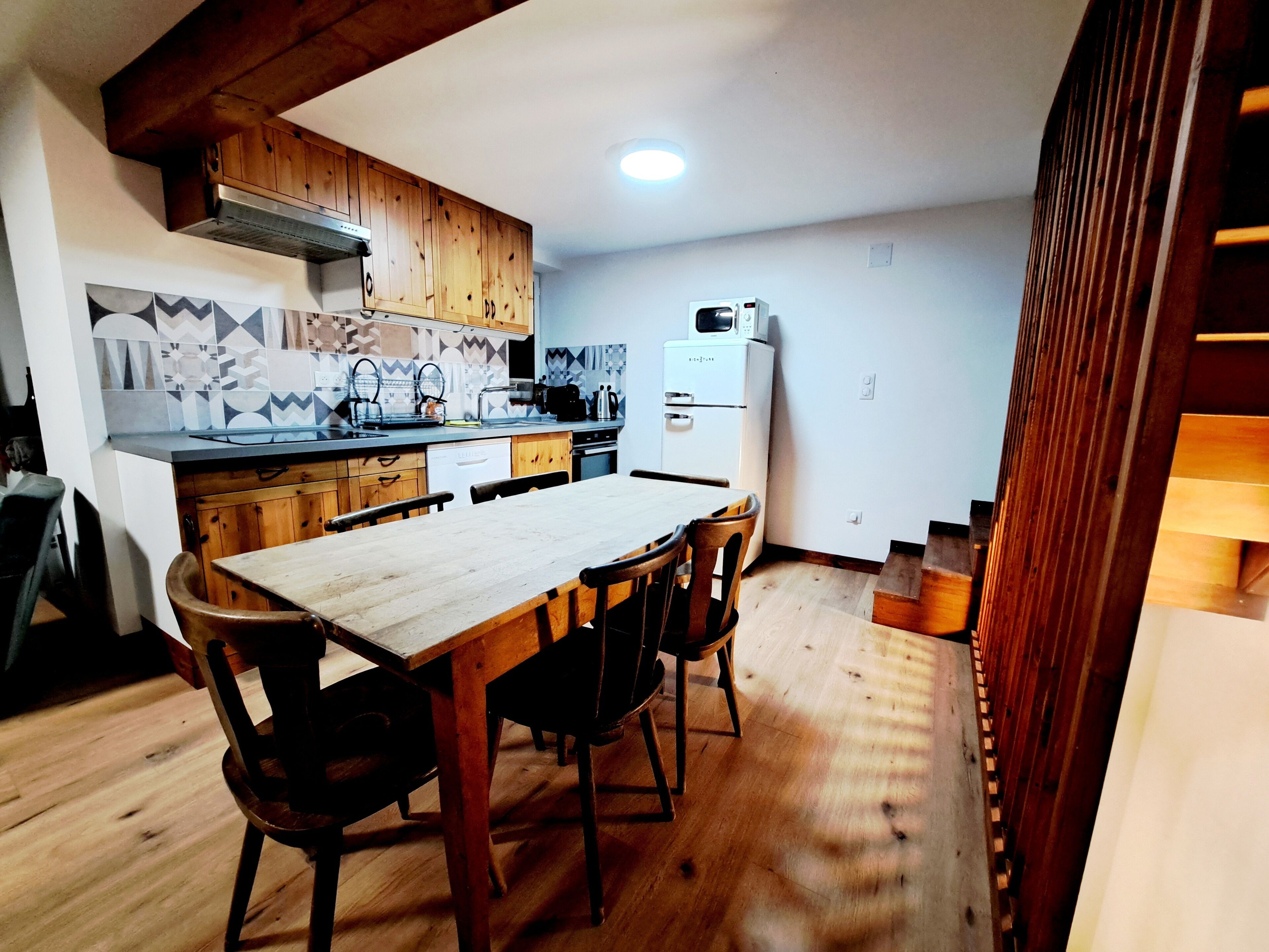 Una cocina compacta con armarios de madera, una isla central y un microondas integrado.