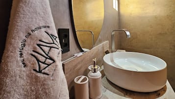 Un baño moderno con un lavamanos ovalado grande, una toalla con texto y un techo de madera.