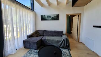 A modern living room with a sofa, a round coffee table, and a painting on the wall.