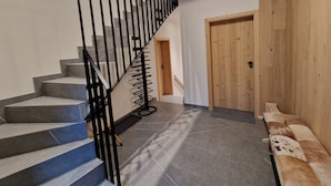 Eine Treppe mit schwarzen Metallgeländern und grauen Stufen, die zu einer Holztür führt.