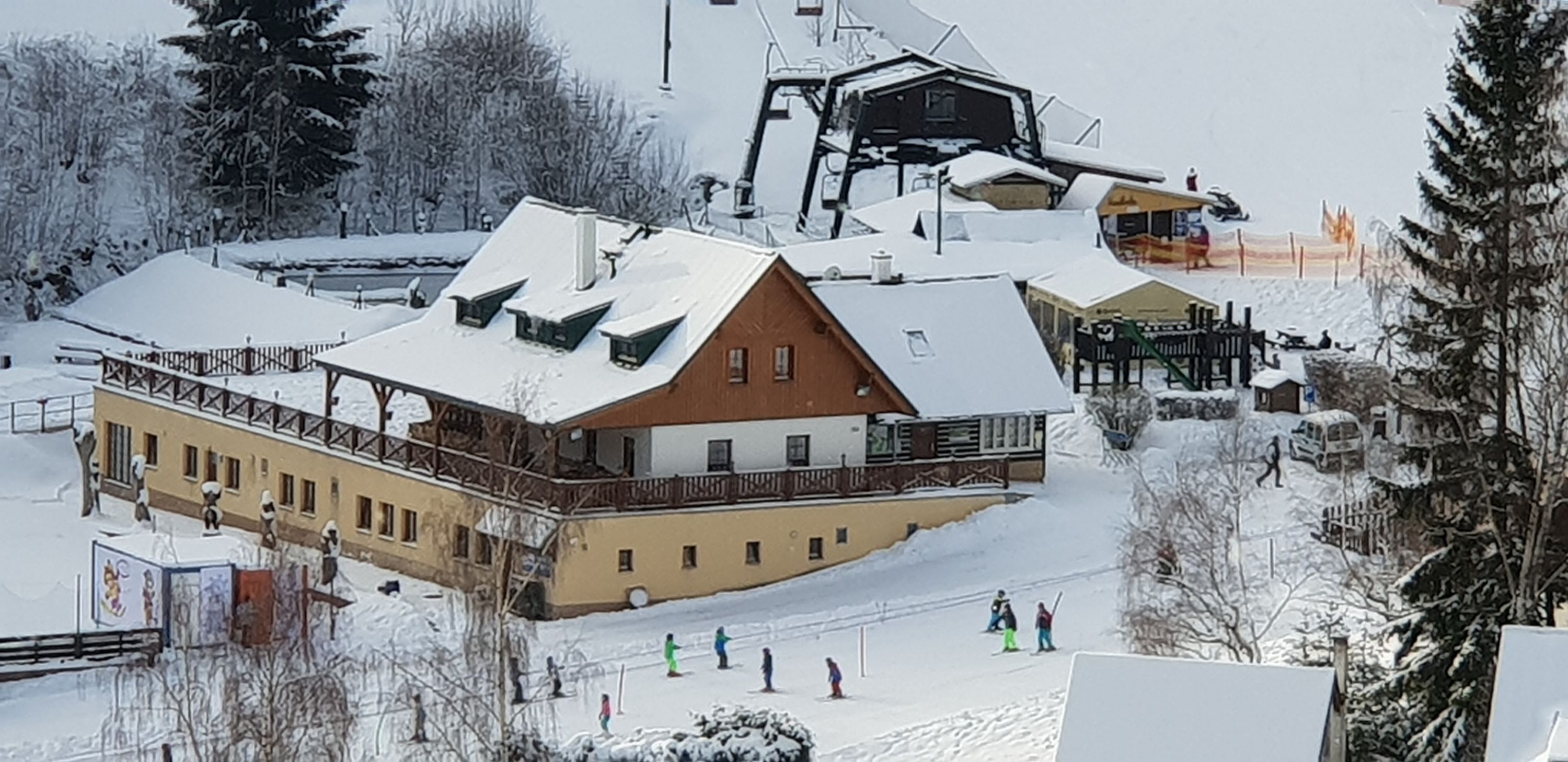 A ski resort with a large building featuring multiple balconies and a ski lift in the background.
