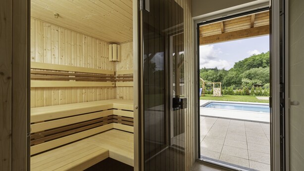 A sauna with wooden benches and a glass door leading to a pool area. - Prosence Kpa250 in Prosecn (Prosečné)