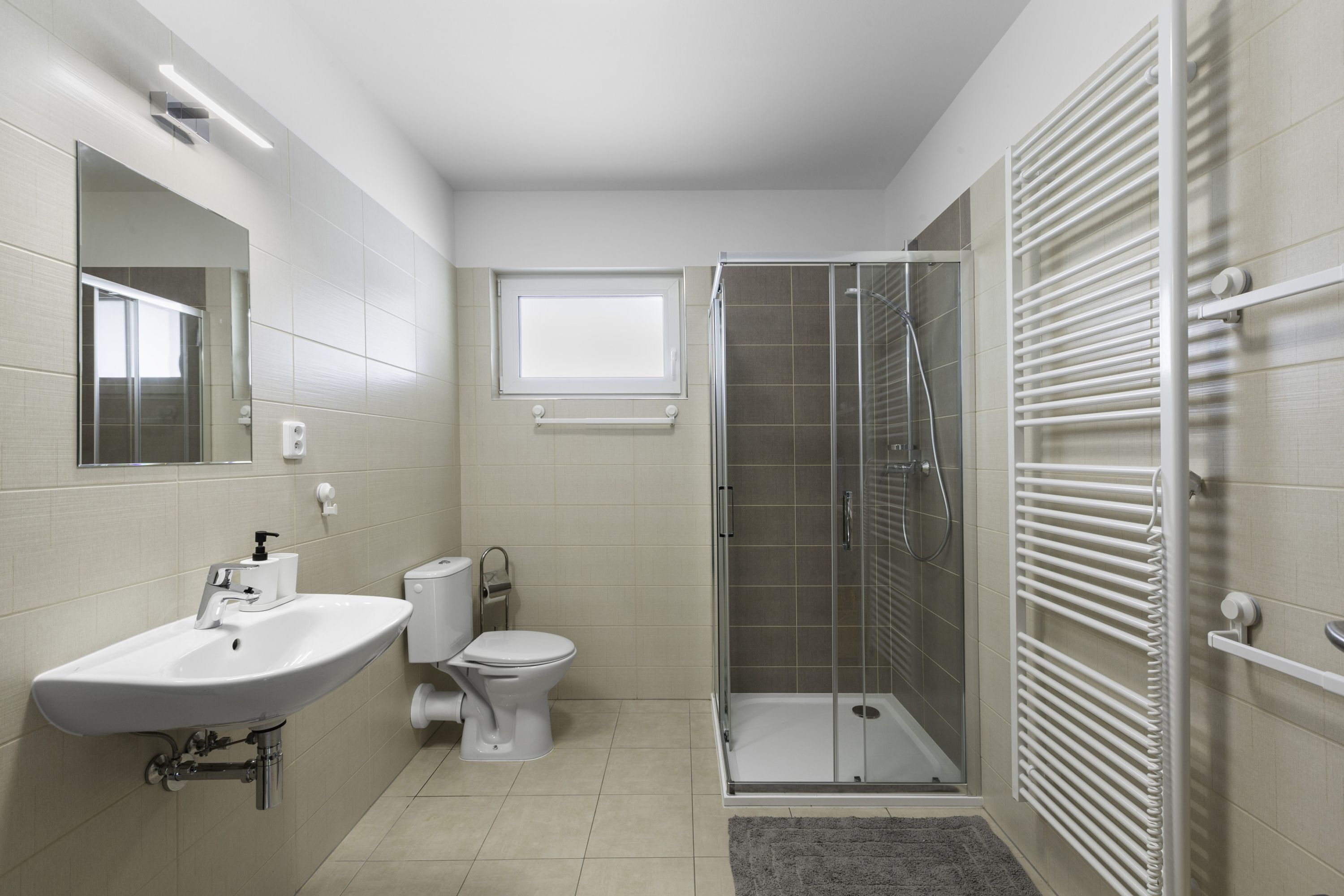 Un baño moderno con lavamanos, inodoro y ducha con mampara de vidrio.